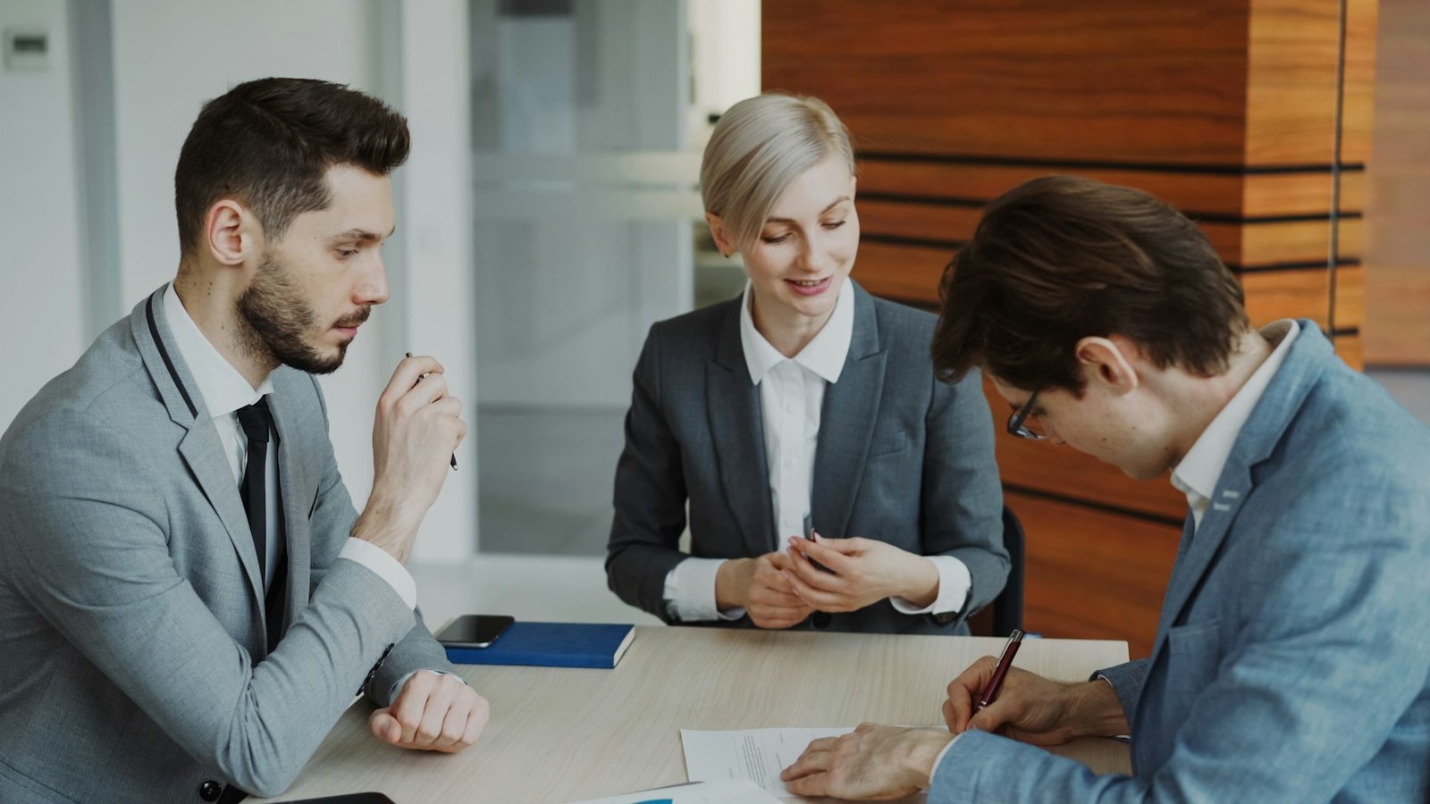 Client signing documents with advisors in a meeting room